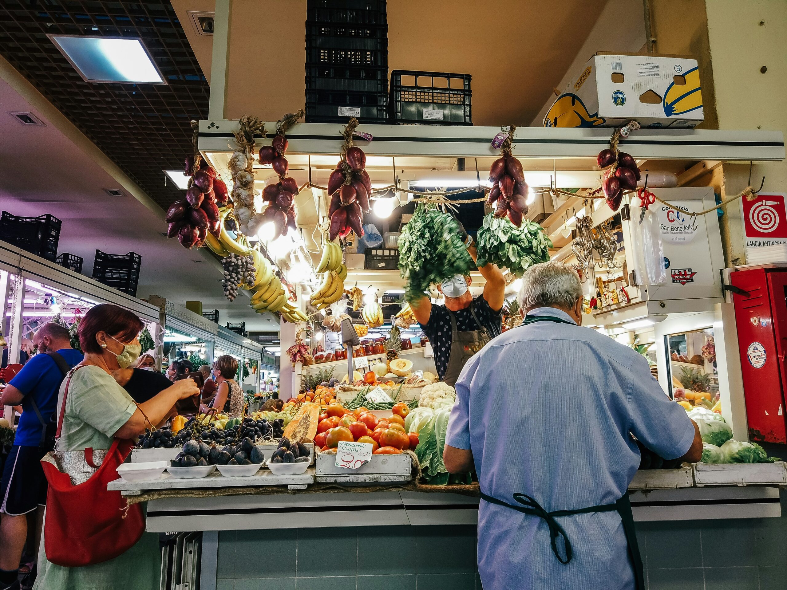 woman in white dress standing in front of vegetable display